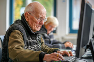 Bild vergr&ouml;&szlig;ern: Ein &auml;lterer Mann sitzt vor einem Computer. Er tippt etwas.