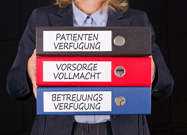 Eine Frau h&auml;lt drei Ordner fest. Darauf steht Patientenverf&uuml;gung, Vorsorgevollmacht, Betreuungsverf&uuml;gung.