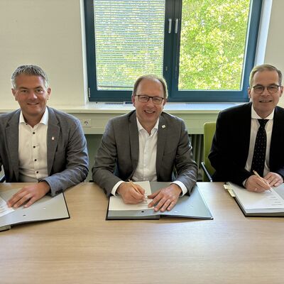 Drei M&auml;nner unterschreiben einen Vertrag.