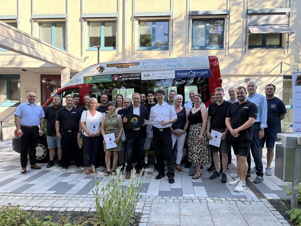 Vor einem Feuerwehrauto stehen viele Leute. Sie haben das mit ihren Anzeigen bezahlt. 