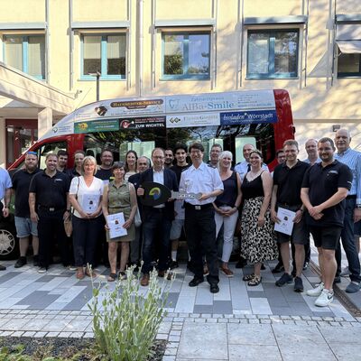 Vor einem Feuerwehrauto stehen viele Leute. Sie haben das mit ihren Anzeigen bezahlt. 