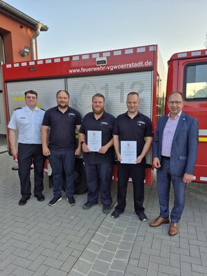 Bild vergr&ouml;&szlig;ern: Mehrere M&auml;nner stehen vor einem Feuerwehrauto.