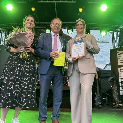Auf einer B&uuml;hne stehen zwei Frauen und ein Mann. Sie er&ouml;ffnen zusammen ein Fest. 