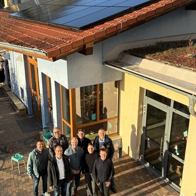 Vor einem Geb&auml;ude stehen mehrere Menschen. Auf dem Dach sieht man eine neue Solaranlage. Die wird heute eingeweiht. 