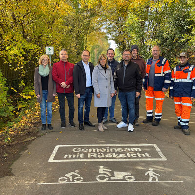 Mehrere Personen stehen auf einem Weg. Dort sind ein Radfahrer, ein Traktor und ein Fu&szlig;g&auml;nger aufgemalt. Dar&uuml;ber steht "Gemeinsam mit R&uuml;cksicht". Alle sollen den Weg gemeinsam nutzen und dabei aufeinander R&uuml;cksicht nehmen. 
