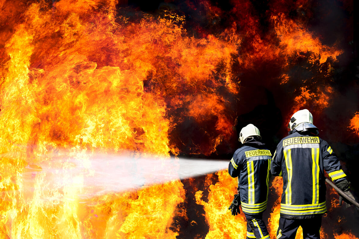Zwei Feuerwehrleute l&ouml;schen ein gro&szlig;es Feuer.